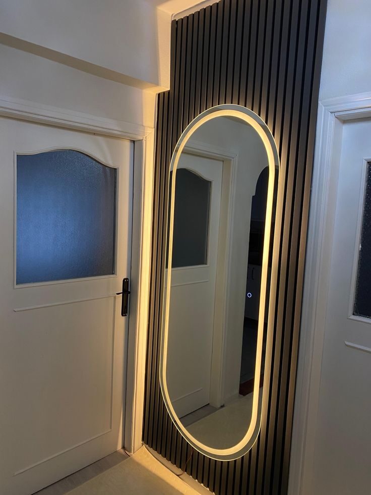 Capsule-shaped LED bathroom mirror with cool white halo lighting above a marble vanity